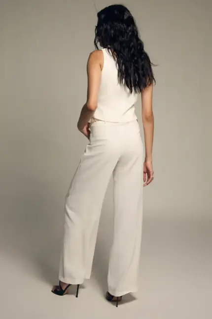 El Pantalón Jane B redefine la elegancia con un diseño versátil y lleno de intención. Confeccionado en un sofisticado tono crudo, presenta una silueta de tiro alto que estiliza la figura y alarga visualmente las piernas, aportando una caída fluida y pulida. Su diseño recto crea una línea limpia y atemporal, perfecta para looks de sastrería impecable. Pero su verdadero encanto reside en su doble funcionalidad: incorpora tiras ajustables en el bajo que permiten transformar la silueta. Puedes llevarlo en versión recta, retirando o soltando las tiras para un acabado clásico, o ajustarlas para crear un moderno efecto globo que aporta volumen y carácter al conjunto. Versátil y sofisticado, es la pieza ideal para combinar con la blazer y chaleco a juego y construir un traje contemporáneo, o para llevarlo con tops más ligeros y convertirlo en el protagonista absoluto del look. Un pantalón diseñado para adaptarse a tu estilo y a cada ocasión.